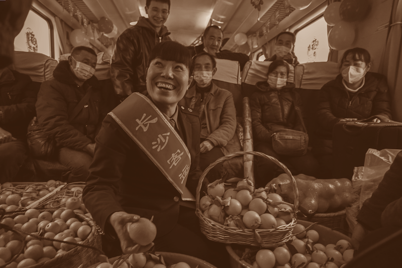 2023年1月18日：农历腊月二十七这天，7272次列车的车厢里放满了水果，列车值班员程雅婷正满脸喜气地帮助村民直播销售。郭立亮/摄