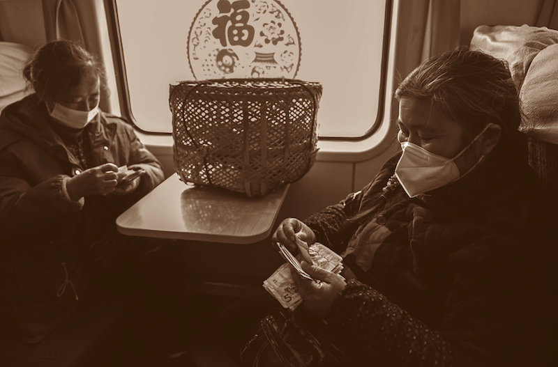 2023年1月18日：节前气氛浓，腊月二十七的下午，卖完菜的村民在乘坐的7271次列车上对当天的卖菜收入进行清点，迫不及待看看卖了多少钱。郭立亮/摄